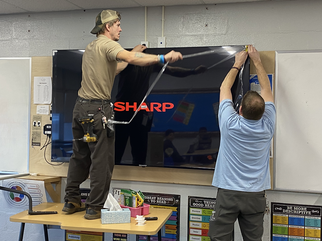 Custodians install new larger classroom televisions with anti-glare coating throughout the school. Installation was carefully scheduled before and after school hours to avoid class interruptions.